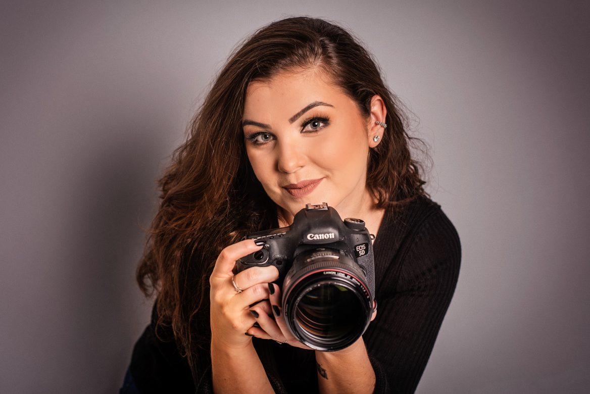 Retrato em estúdio de fotógrafa, com a câmera na mão, realizado em Blumenau - Santa Catarina.